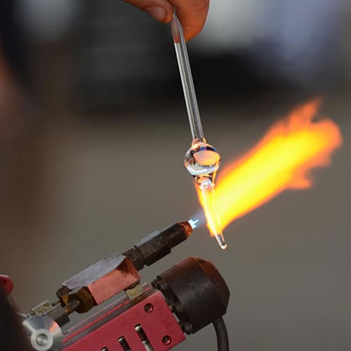 CC BY-SA. endlesspics. man heating clear glass in a small torch. 