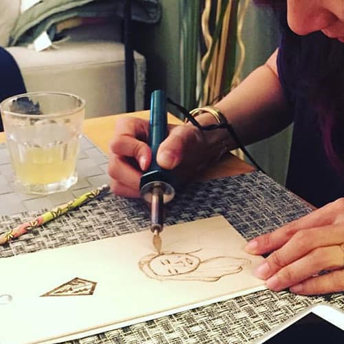 woman wood burning a portrait to sell 