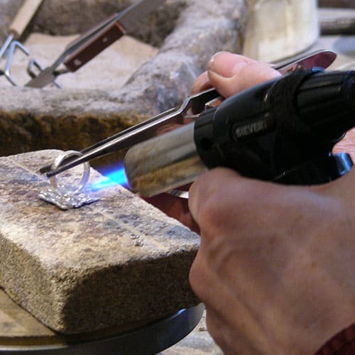 jeweler using torch to solder a ring